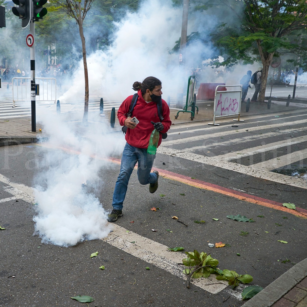 A protester runs and dodges tear gas fired by police on the first day of the Colombian 2021 National Stoppage