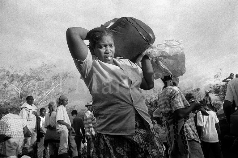 A woman carries a bag on her shoulders amongst boat passengers