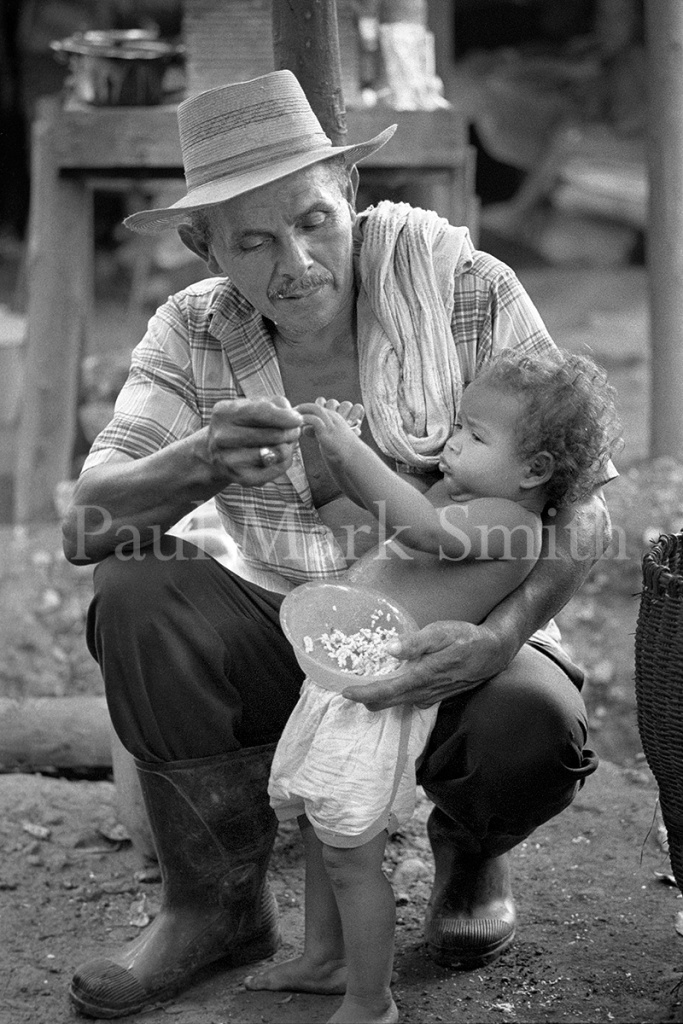 A grandfather gives his granson food from a bowl