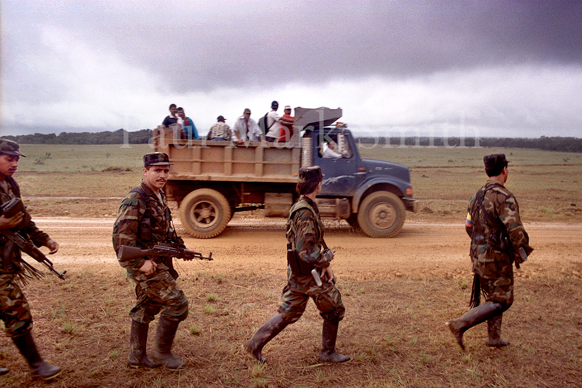 Line of walking guerrillas and a dumper truck carrying passengers