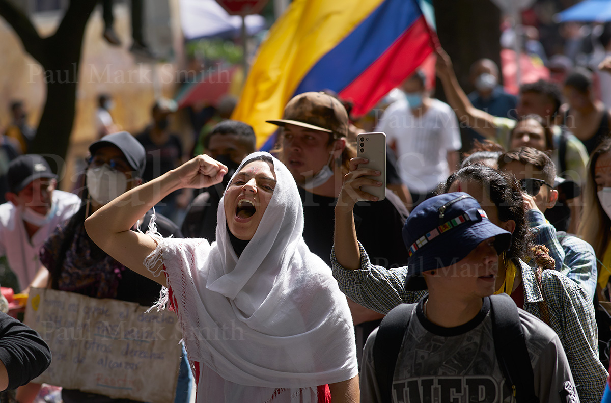 Woman chants with clenched fist and Colombian flag
